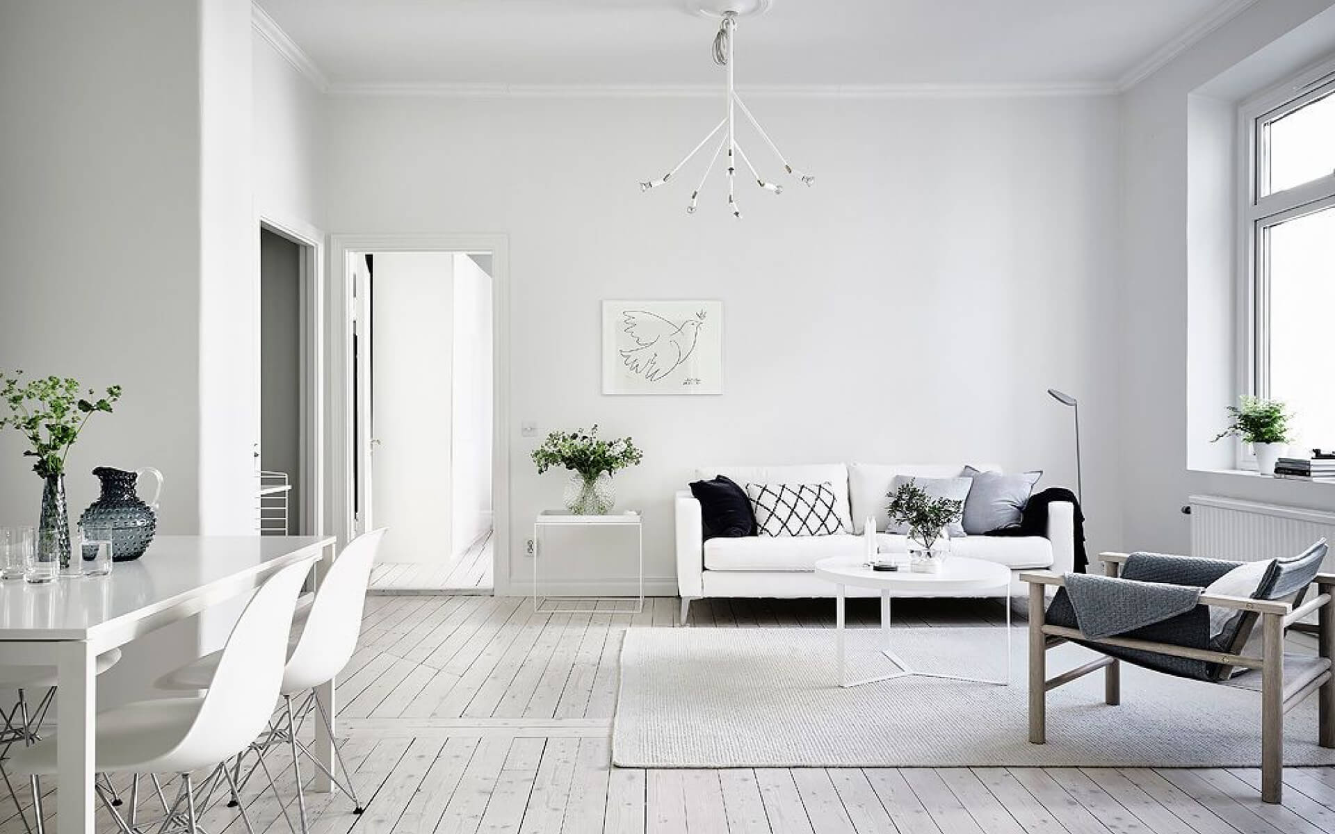Living room in a minimalistic style, decorated with plants and white tones.