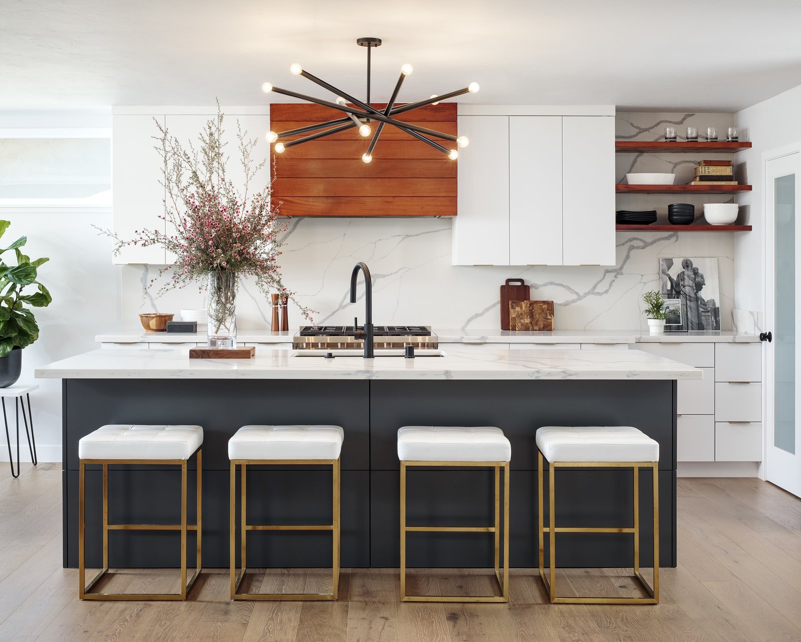 White cabinetry and white marble match against wooden accents in a Contemporary kitchen