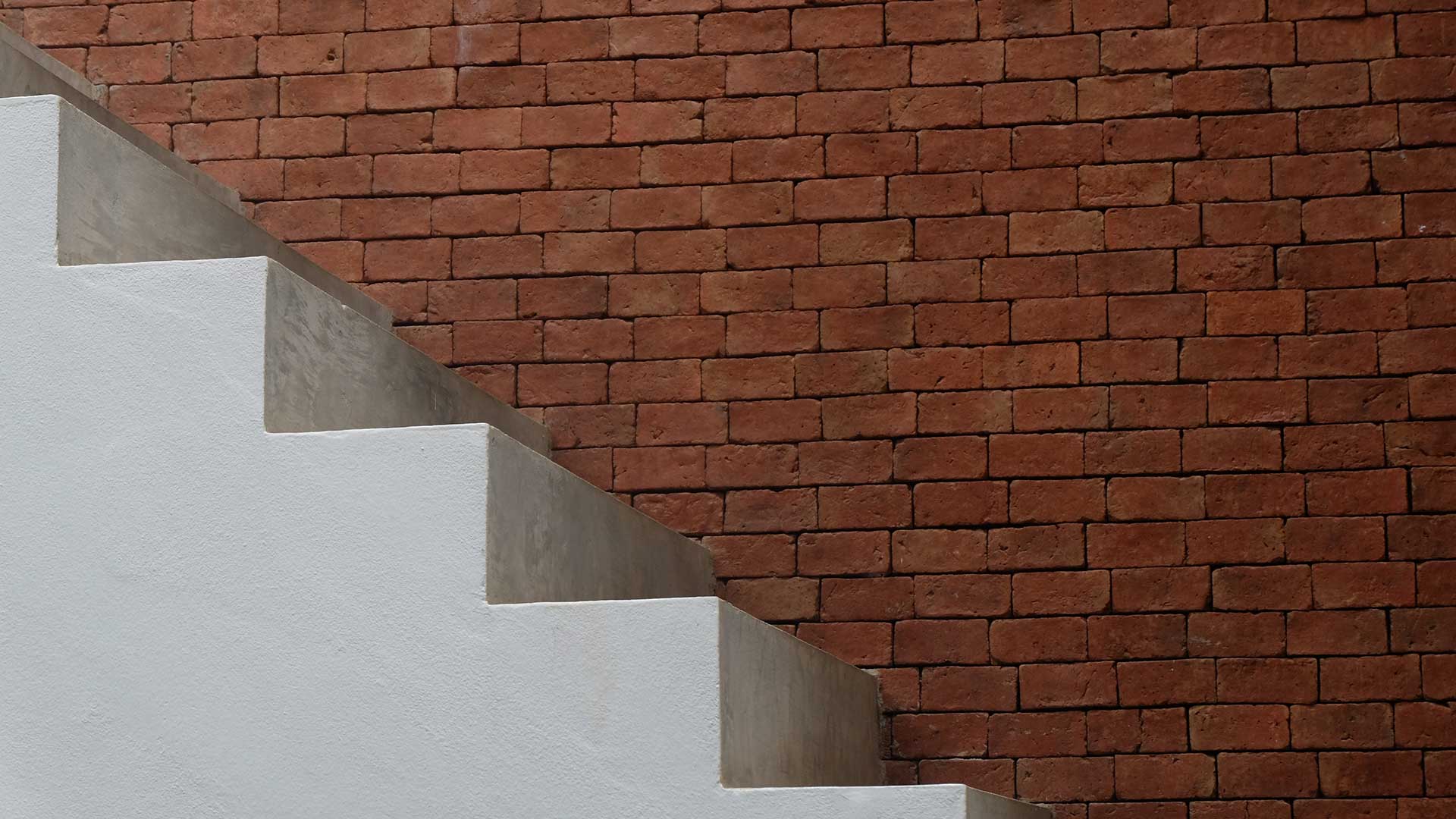 Concrete flooring staircase against a bare brick wall