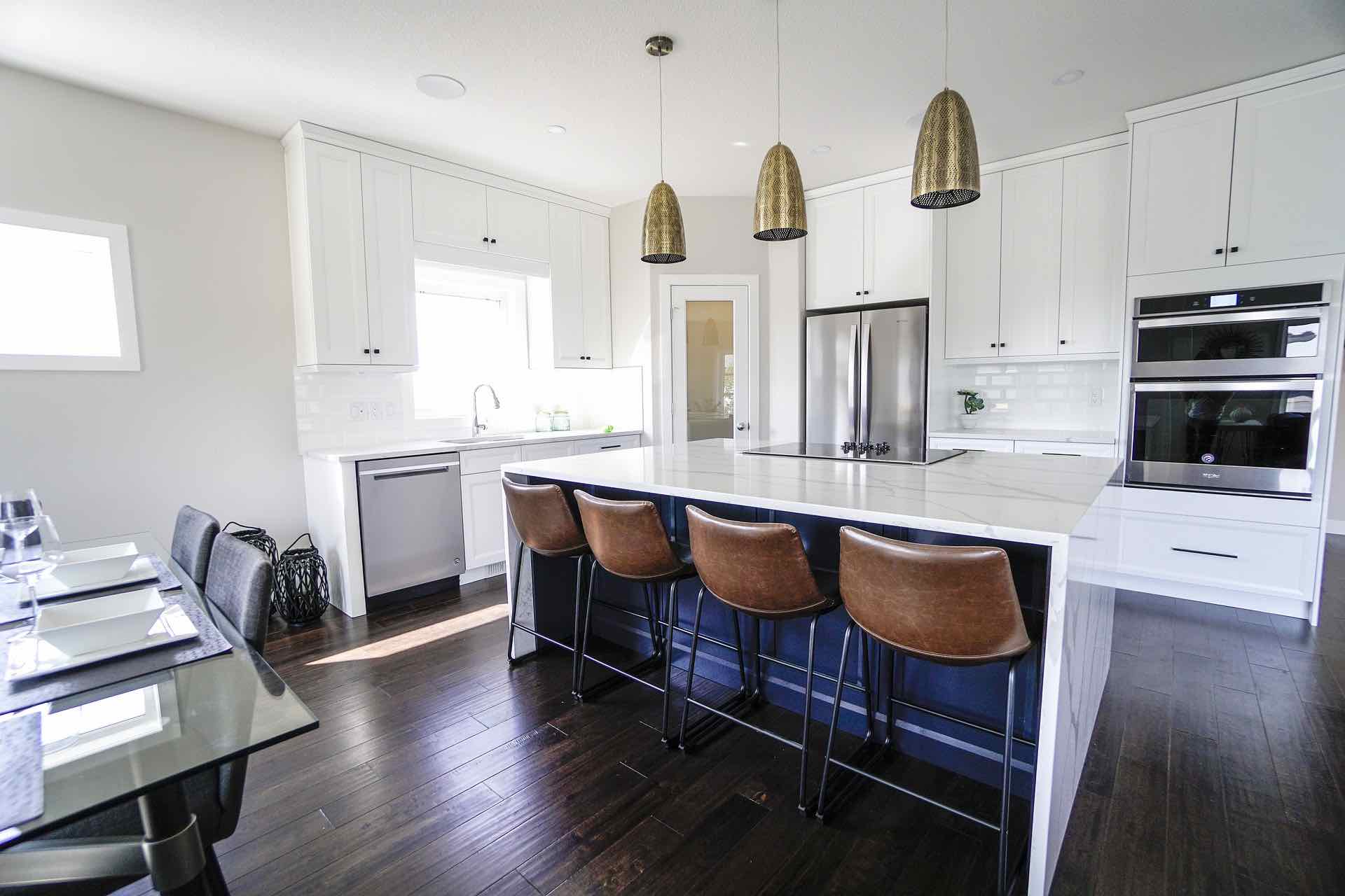Bullet shaped pendant lights encased in bronze metal elevates the space against white cabinets and countertops