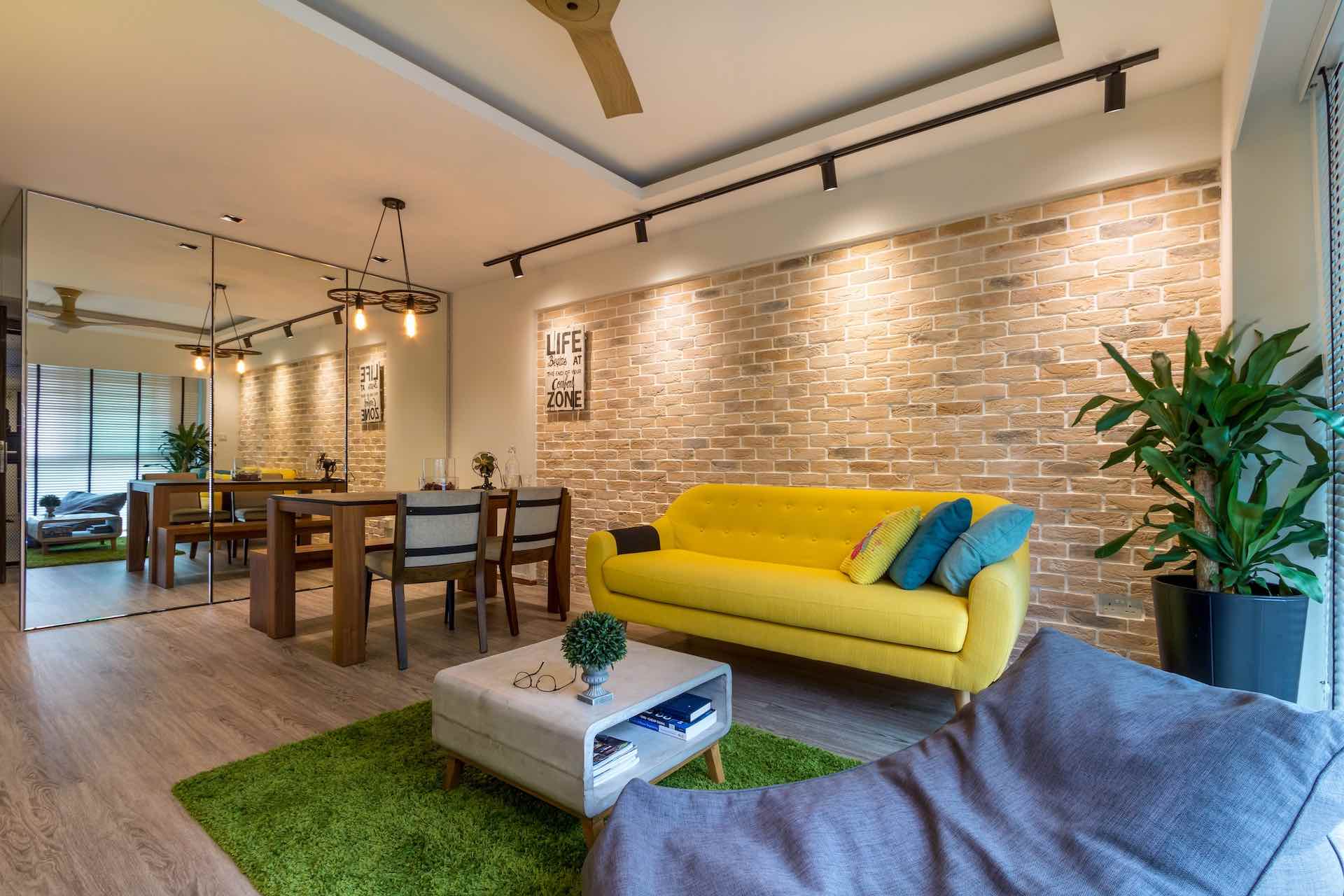 Living room of a Scandustrial style with vibrant honey yellow couch leaned against exposed brick accent wall coupled with grass