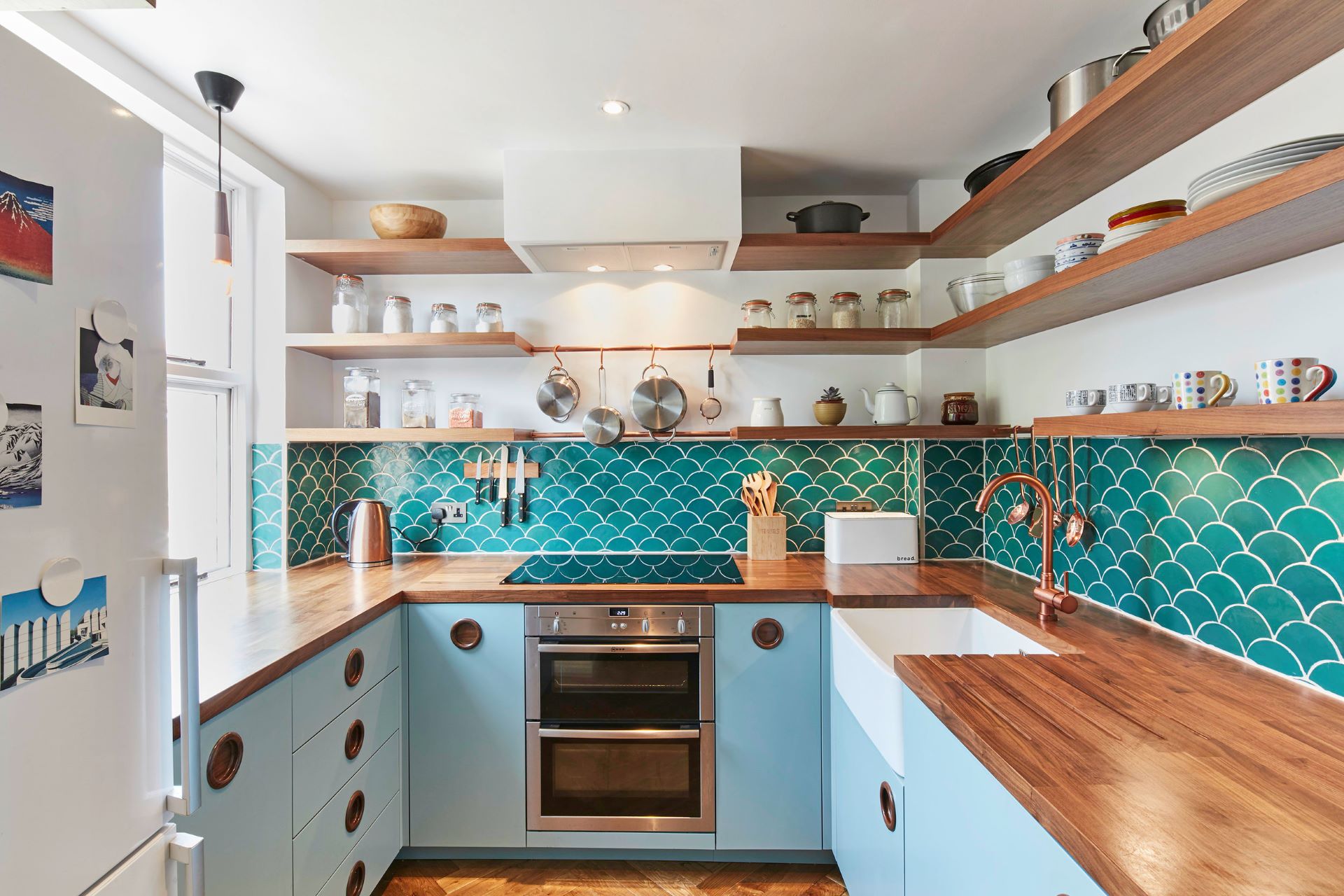 Blue themed MCM kitchen with wooden countertop and shelves stocked with dinnerware