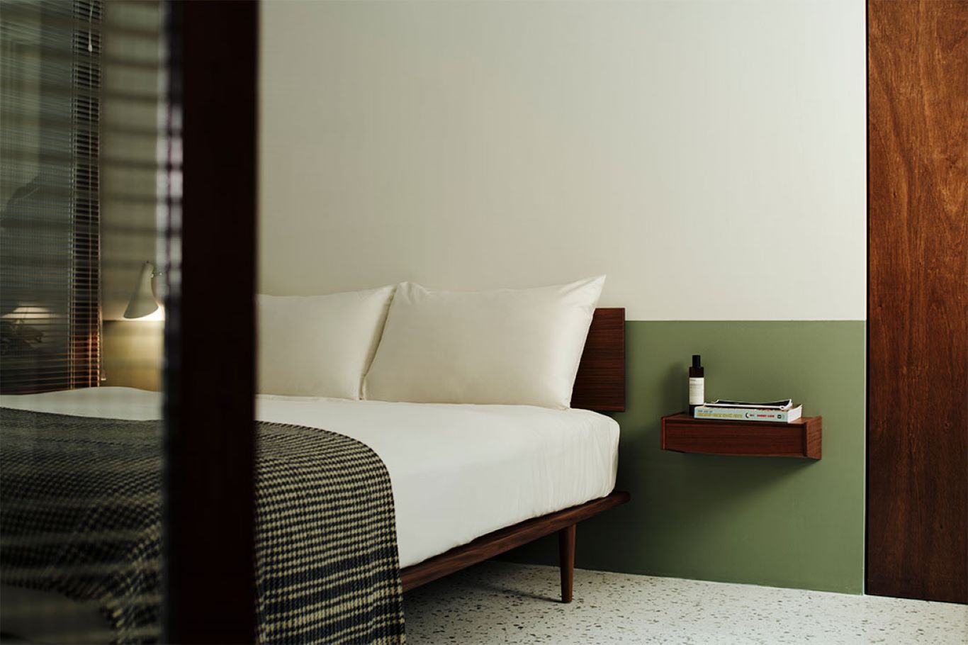 Bed frame on tapered legs atop marble flooring with simple wooden furnishings