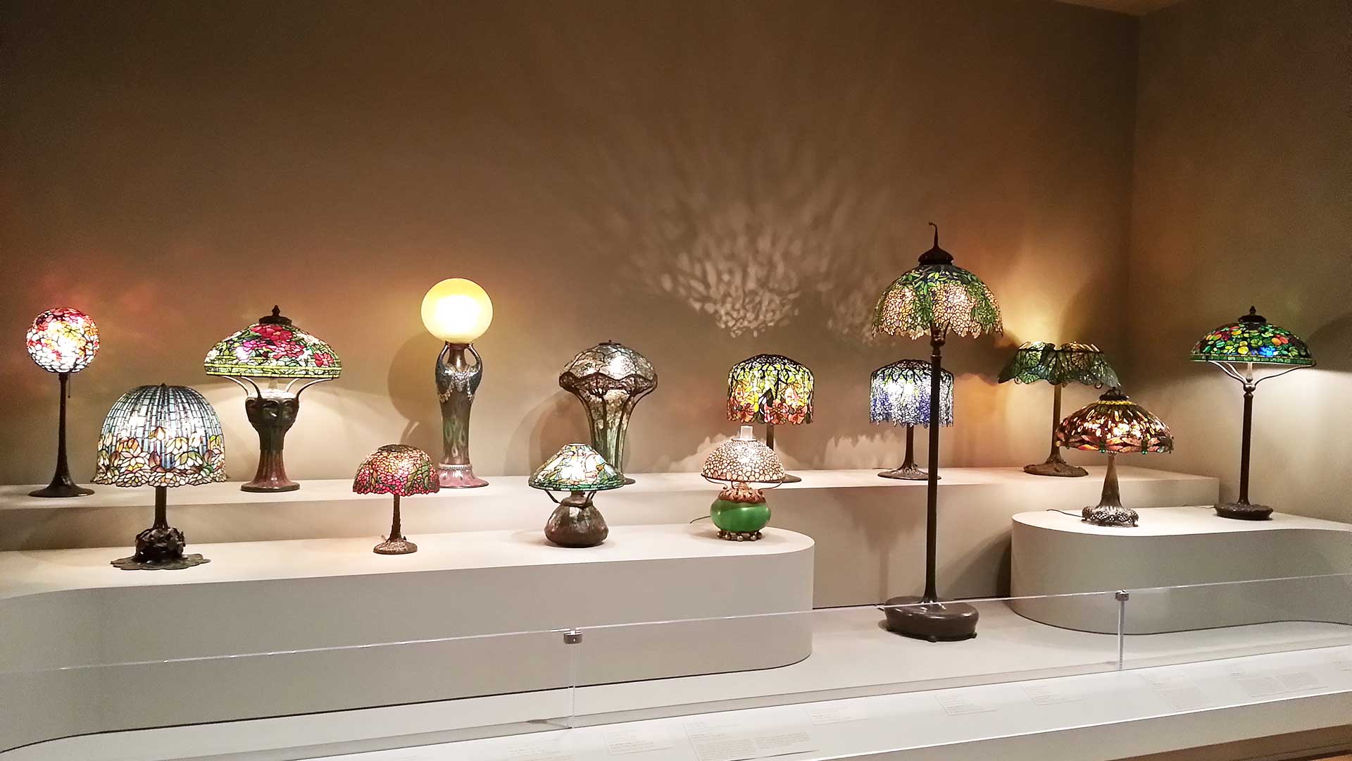 A range of Tiffany lamps in small and large sizes having different colored stained glass patterns.