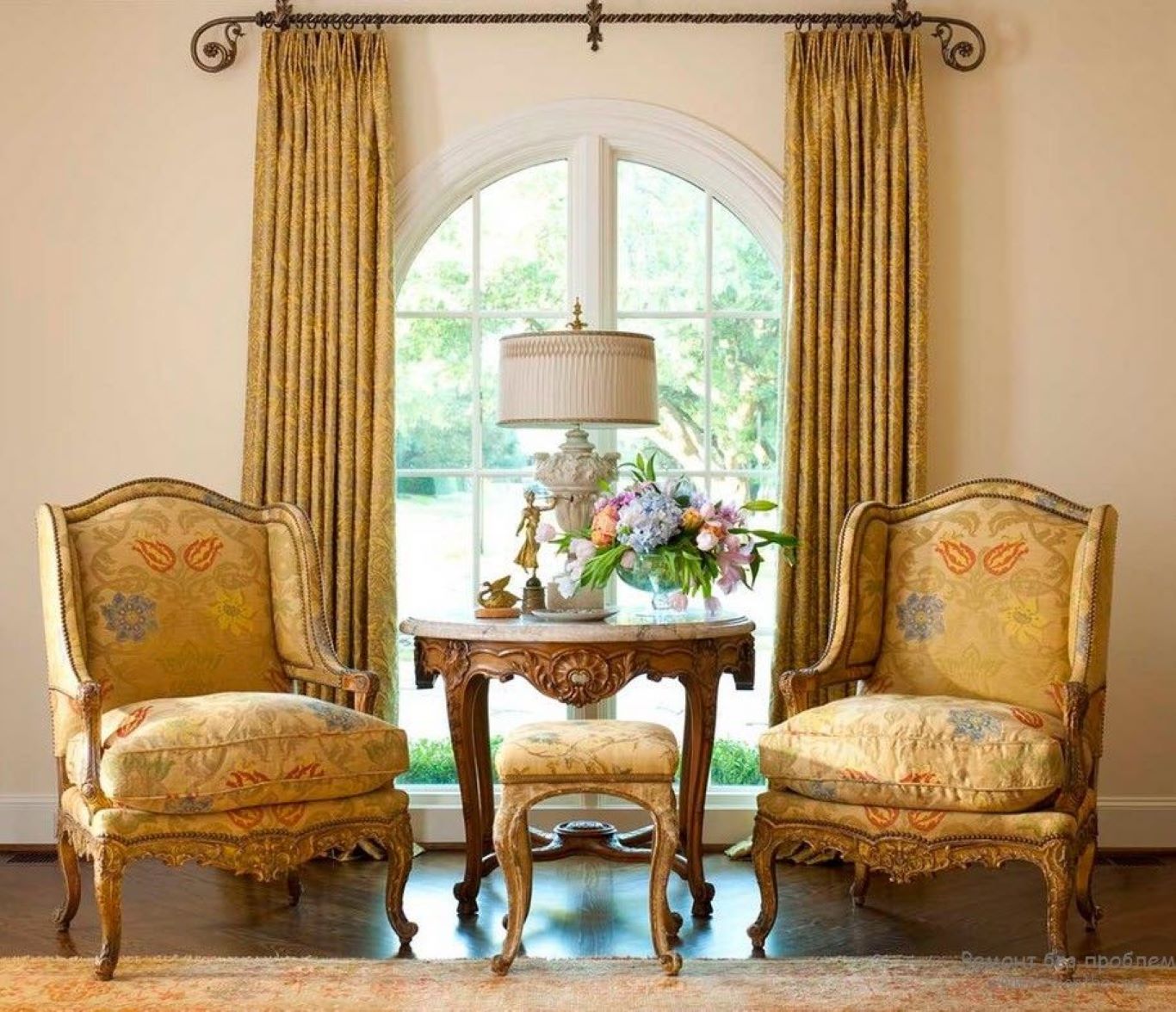 Intricate-design floor-to-ceiling curtains and two matching-toned ornate wooden chairs in a Victorian style lounge.