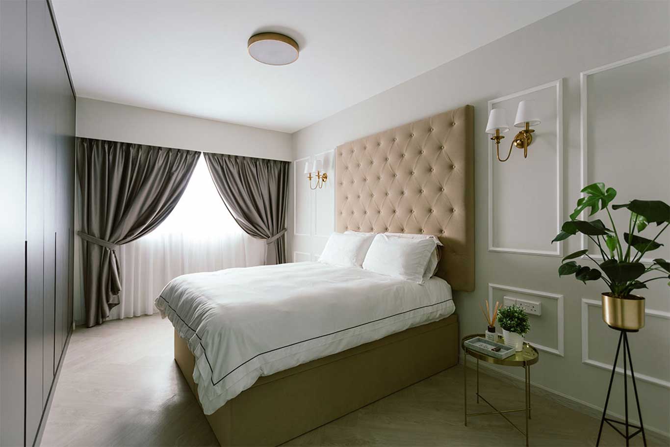 Modern Victorian bedroom with lightly- quilted headboard and sconce wall lights.