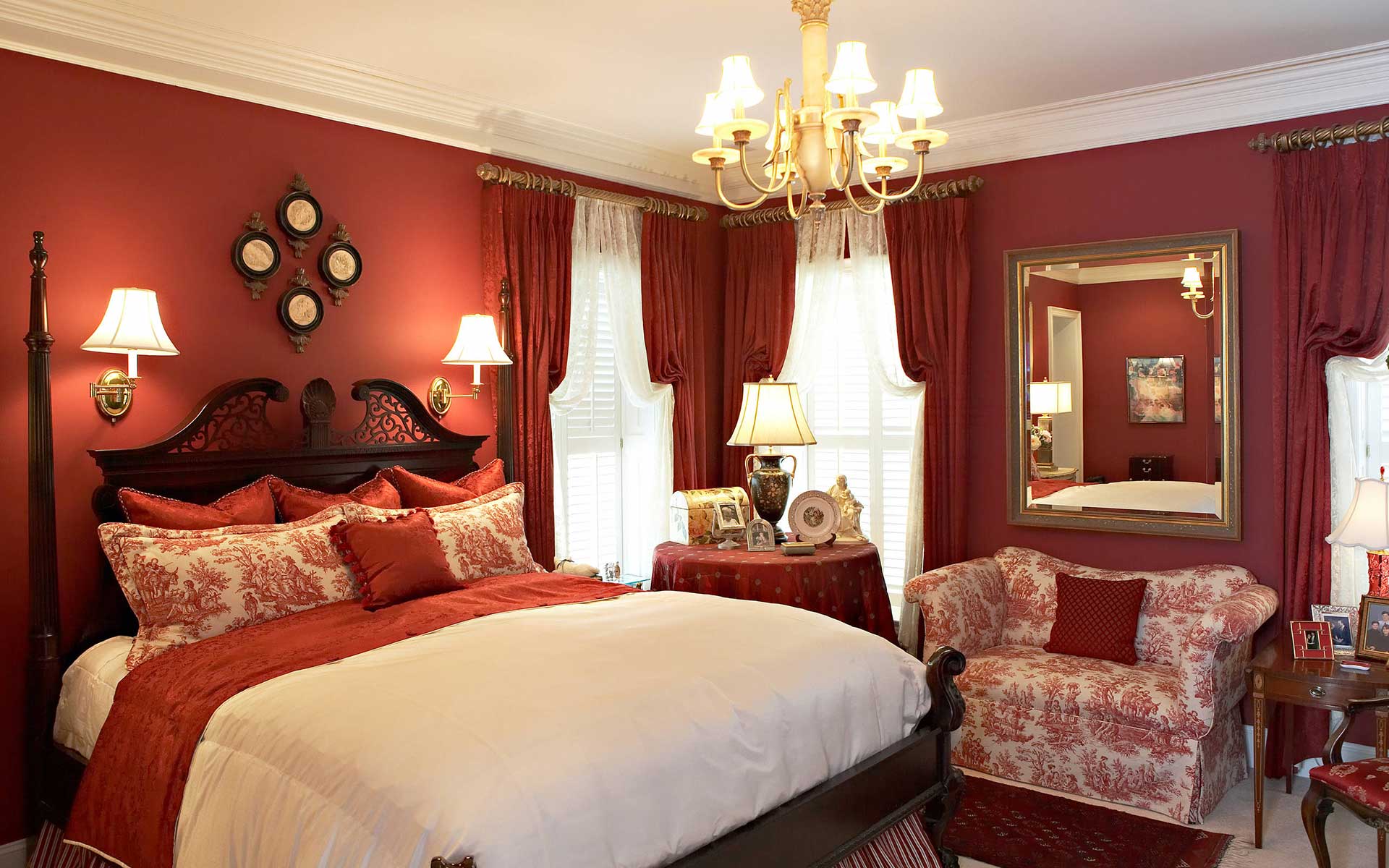 Aristocratic-style bedroom in rich red tones. Printed fabric cushions and sofa add Victorian vibes to the overall design.